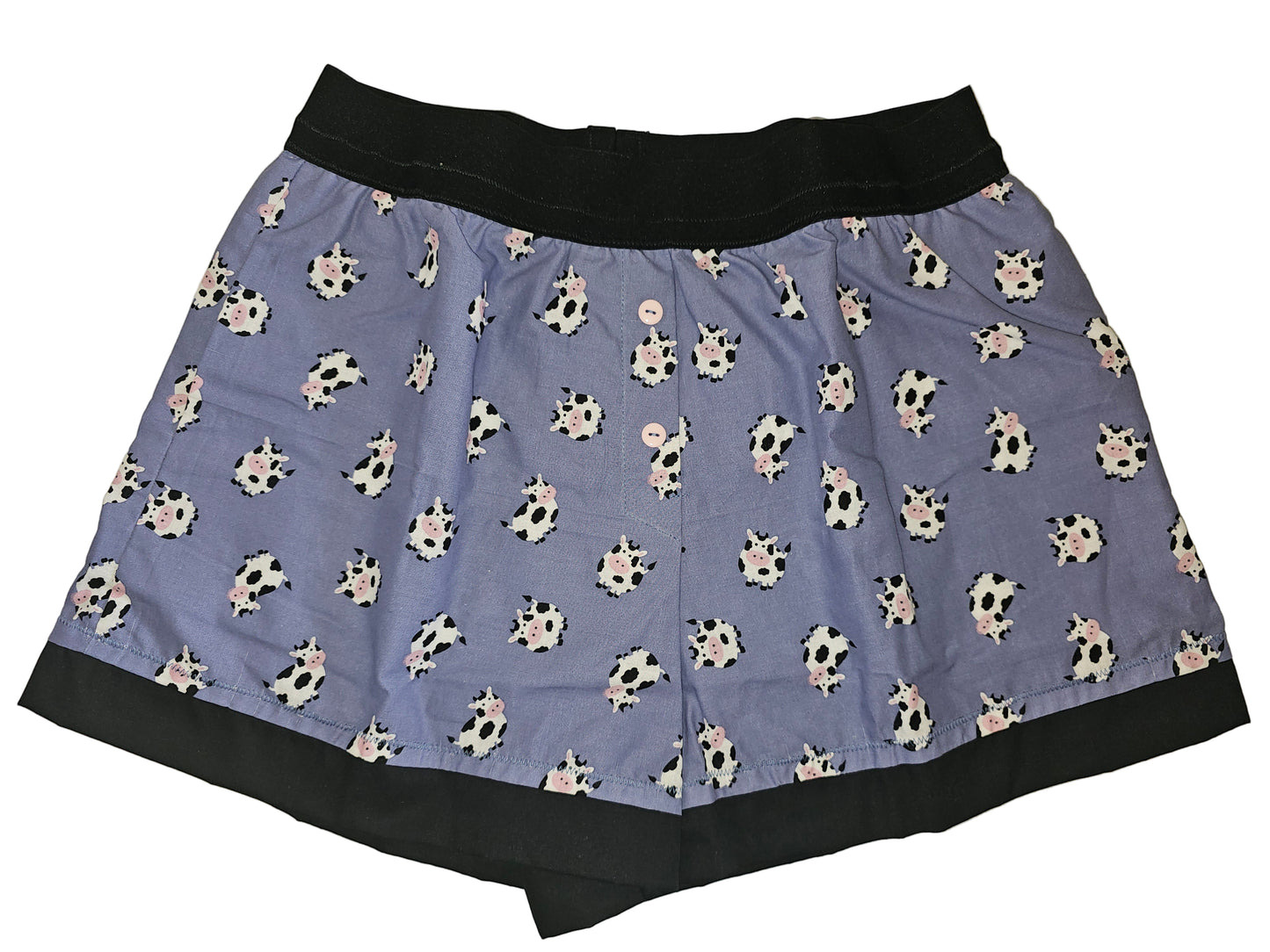 Women’s loungewear boxers in ‘Moo Mood Lounge’ print, featuring adorable black-and-white cows on a periwinkle background, black waistband and hem, soft breathable fabric, deep side pockets, and a handmade cozy fit.
