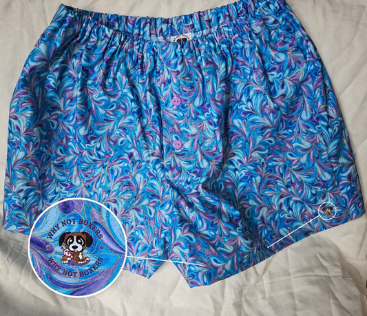Women’s XL boxer shorts with side pockets, featuring a blue and purple marbled swirl pattern, elastic waistband, and front button detail, displayed on a light background; includes a zoomed inset highlighting the “Why Not Boxers” dog logo printed on the fabric.